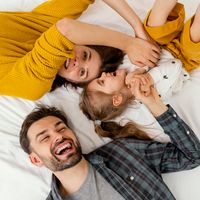 medium-shot-parents-kid-bed-top-view